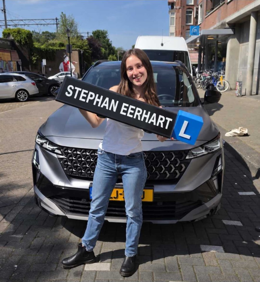 Geslaagde leerling met het bord van Autorijschool Stephan Eerhart