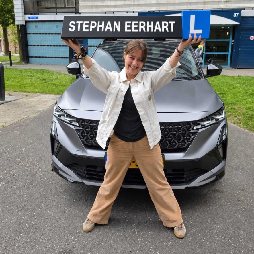 Geslaagde leerling met het bord van Autorijschool Stephan Eerhart