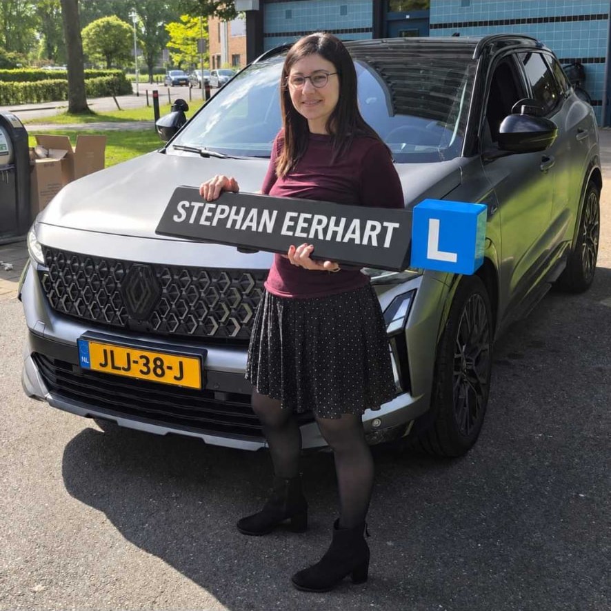 Geslaagde leerling met het bord van Autorijschool Stephan Eerhart